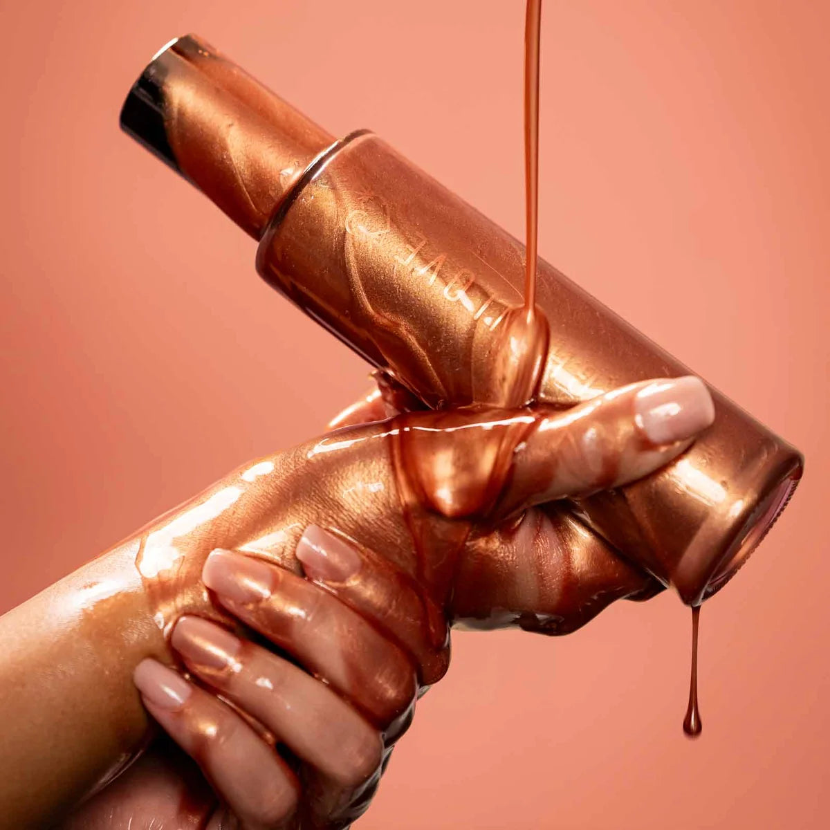 High On Love Shimmering Body Oil being poured over two hands coated in warm bronze shimmer oil against terracotta pink background